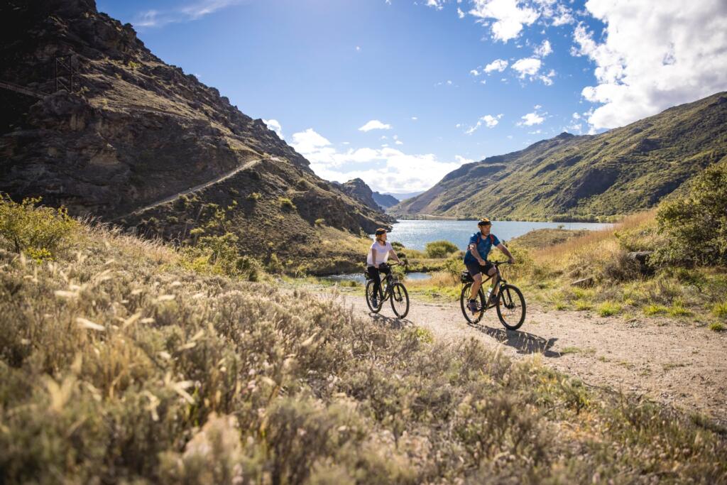 deux cyclistes sur le Lake Dunstan Trail, les montagne en arrière plan