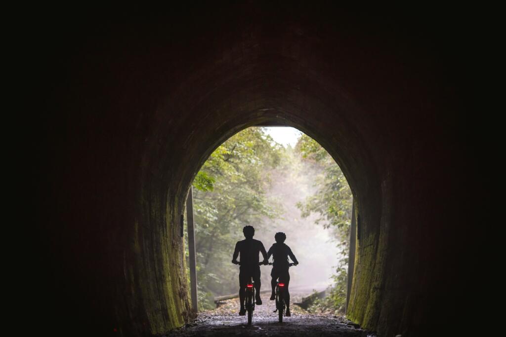 deux cyclistes vus de dos sous un pont au Great Taste Trail 