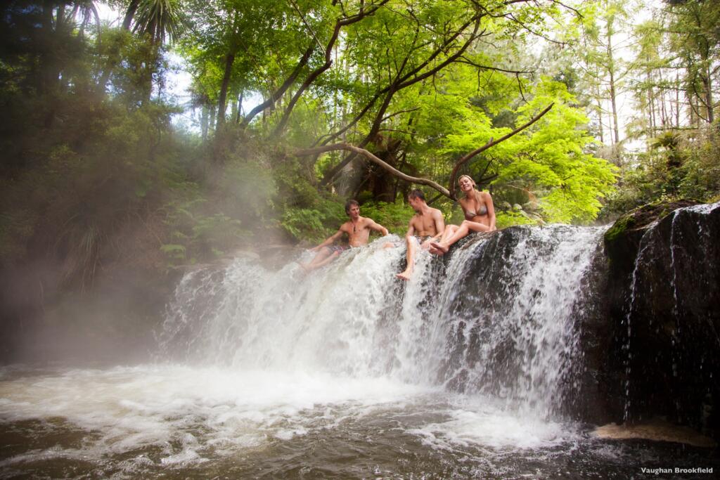 Un groupe d'amis qui se baignent à Kerosene Creek, souce d'eau chaude, à Rotorua en Nouvelle-Zélande