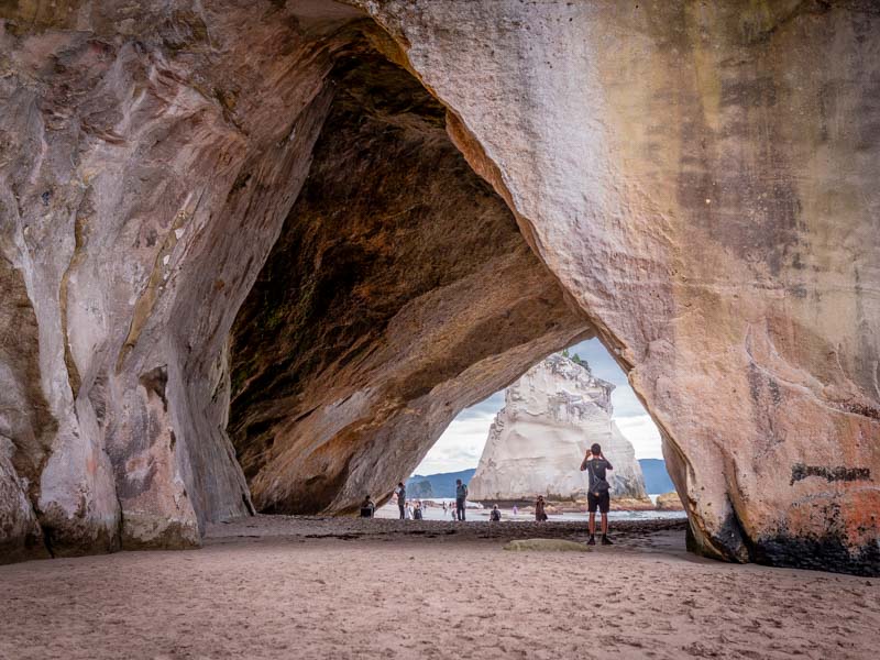 Promeneur sous l'arche de Cathedral Cove en Nouvelle-Zélande