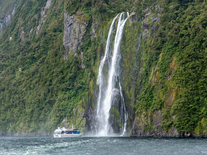 Un bateau au pied d'une cascade dans le fiord de Milford Sound en Nouvelle-Zélande