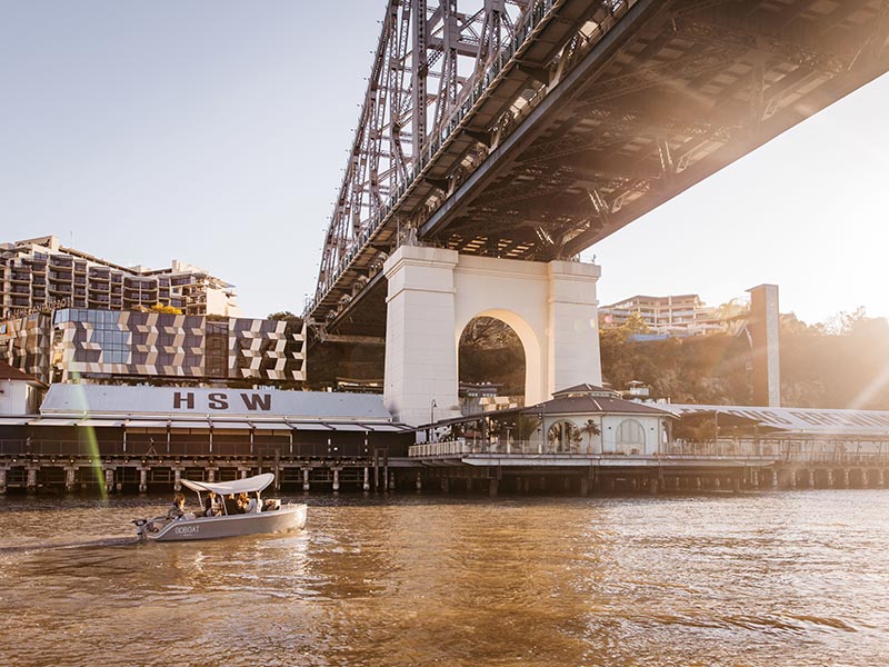 Petit bateau passant sou un pont sur la rivière de Brisbane en Australie