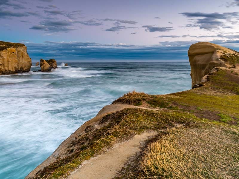 Panorama sur l'océan au coucher du soleil de Tunnel Beach à Dunedin en Nouvelle-Zélande