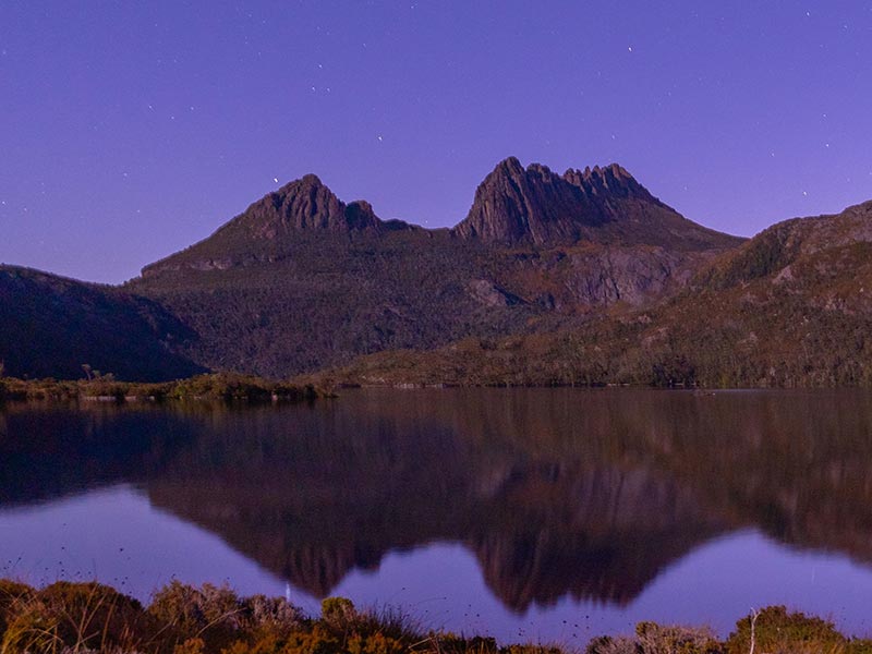 Lac sous un ciel étoilé avec des montagnes en arrière plan dans la parc nation de Cradle Mountain en Tasmanie, Australie