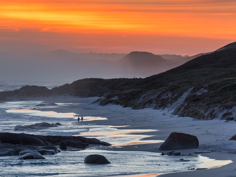 Couple sur une plage désertique au coucher du soleil près d'Albany en Australie